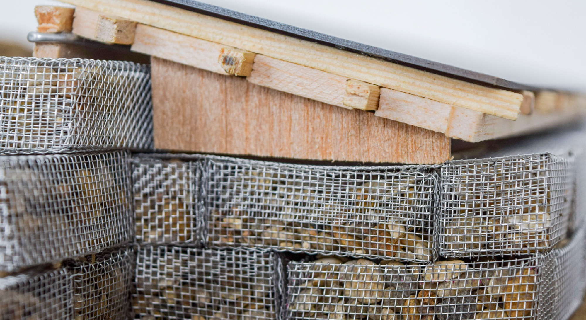Gabions en grillage remplis de galets sous une charpente en bois, vue rapprochée