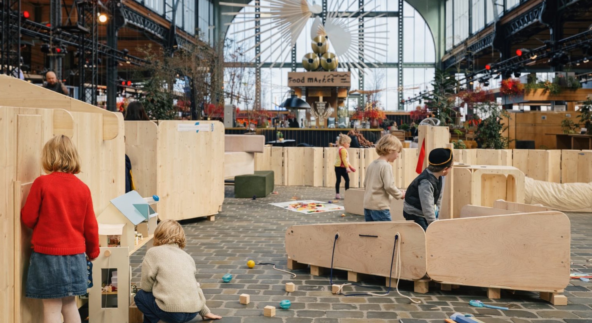 Enfants jouant entre des modules en bois clair dans une grande halle